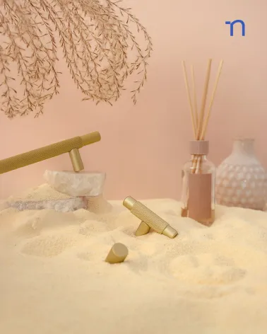 VENDÉ design furniture handle in gold anode/matt gold presented on a sandy decor