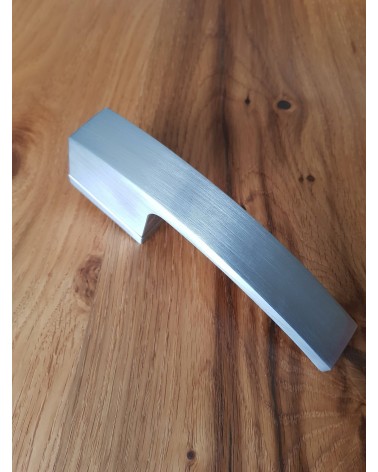 Satin chrome Arc door handle designer handle top angled view placed on a plate