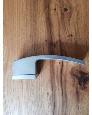 Satin chrome Arc door handle designer handle side view placed on a plate