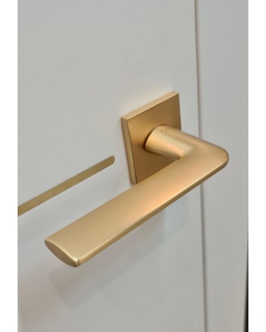 Matt gold STINGER door handle designer handle angled top view mounted on a door