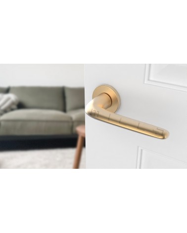 Matt gold AZALIA door handle design handle angled view mounted on a door