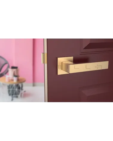 Matt gold PINA design door handle front view mounted on a door