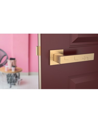 Matt gold PINA design door handle front view mounted on a door
