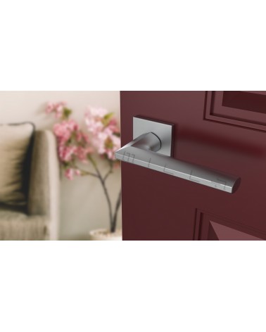 Satin chrome JASMINA door handle designer handle angled view mounted on a door