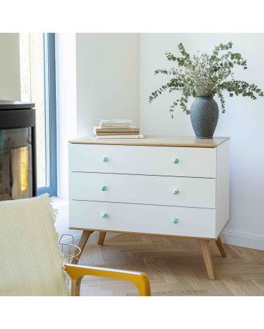 Rich green beech wood furniture knob design handle installed on a white chest of drawers topped with a potted plant