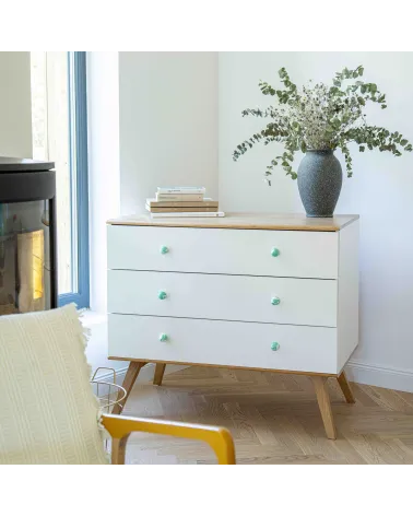 Rich green beech wood furniture knob design handle installed on a white chest of drawers topped with a potted plant