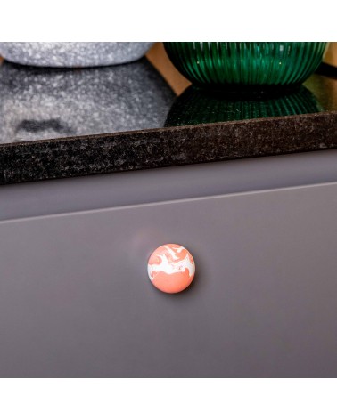 Cherry red beech wood furniture knob design handle close-up view mounted on a kitchen cabinet