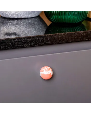 Cherry red beech wood furniture knob design handle close-up view mounted on a kitchen cabinet