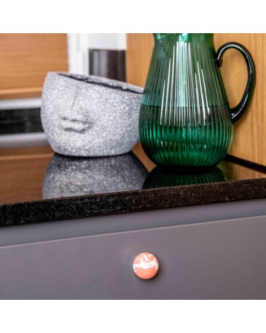 Cherry red beech wood furniture knob design handle fixed on a grey cabinet front beneath a worktop