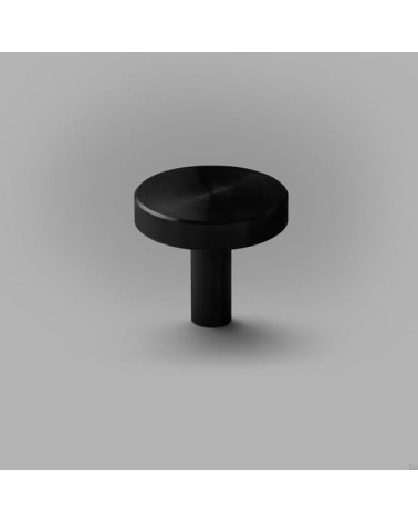Black NENA M furniture knob, designer handle placed on a flat surface