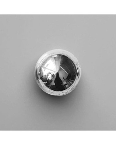 Polished chrome ODETE M furniture knob, designer handle placed on a grey surface
