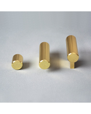 Polished gold AVANTI furniture knob designer handle placed on a grey surface