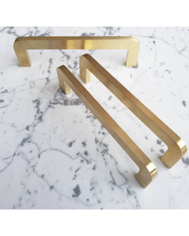 Brushed brass ISA furniture handle designer handle trio placed on a patterned surface