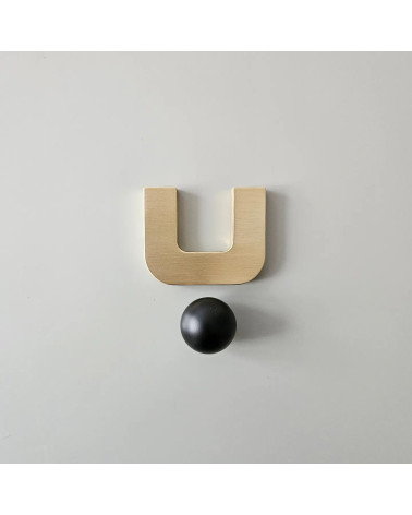 Polished gold ISA XS furniture handle designer handle with black sphere front view on light surface