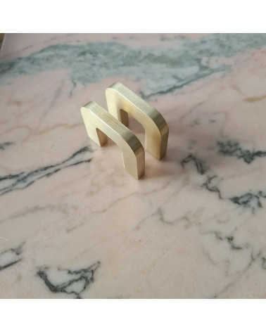 Polished gold ISA XS furniture handle design handle diagonal perspective view laid flat on a marble surface