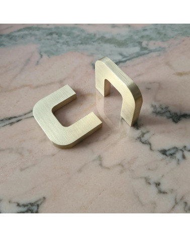 Polished gold ISA XS furniture handle design handle positioned perpendicularly on a marbled surface
