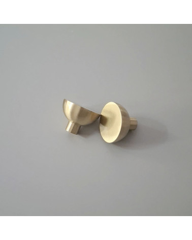 Polished gold LUNA M furniture knob design handle positioned on a plate