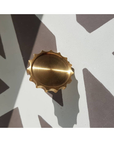 LEXI polished gold furniture knob designer handle large model front view slightly tilted placed on patterned background