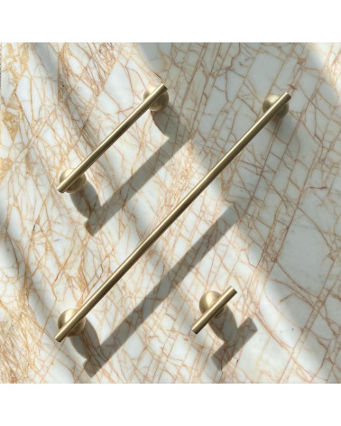 Brass furniture knob model 04 designer handle on a marble surface accompanied by aligned long handles