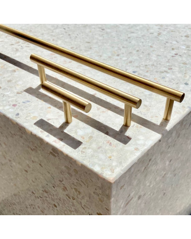 Brass T-Bar furniture knob design handle side view on a stone surface with handles aligned in the background