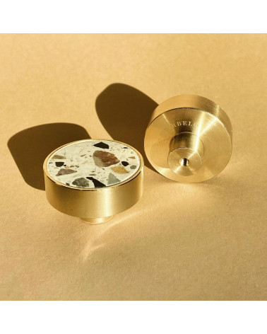 Brass and Terrazzo furniture knob designer handle perspective view on a beige surface surrounded by soft light