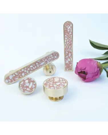 Brass and Pink Terrazzo furniture knob designer handle arranged next to a flower on a white background