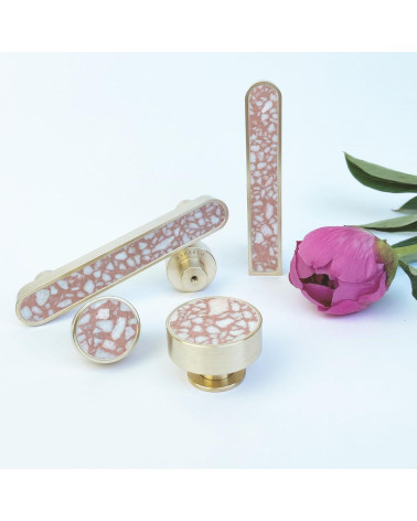 Brass and Pink Terrazzo furniture knob designer handle arranged next to a flower on a white background