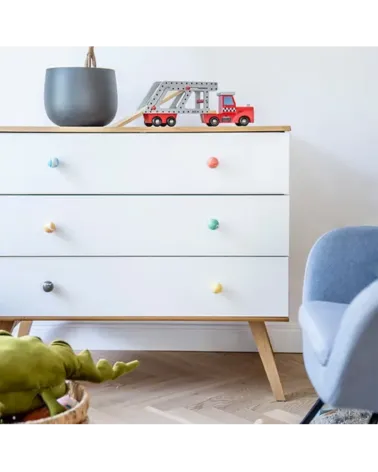Rich green beech wood furniture knob designer handle mounted on a white chest of drawers near an armchair