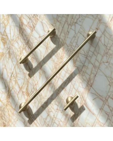 Brass furniture knob model 04 design handle on a marble surface accompanied by aligned long handles