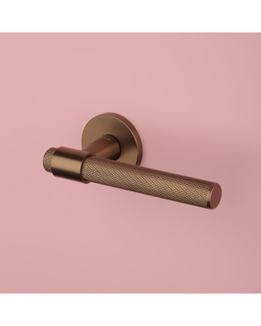 GOYA light brown door handle designer handle top angled view on pink background